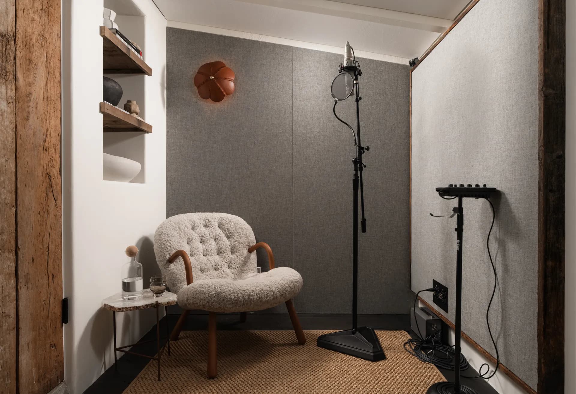 Cozy reading corner featuring cream tufted vintage armchair, professional studio lighting, built-in shelving, and woven rug House Rupert interior design Santa Barbara and Montecito