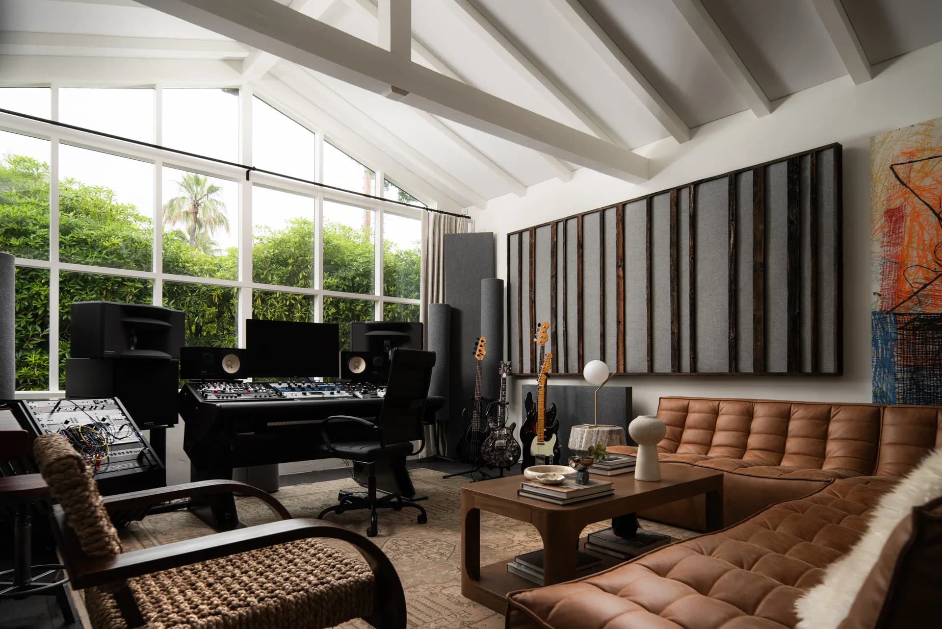 Modern music studio with exposed white ceiling beams, tufted cognac leather sofa, professional audio equipment and guitars, House Rupert interior design Santa Barbara and Montecito