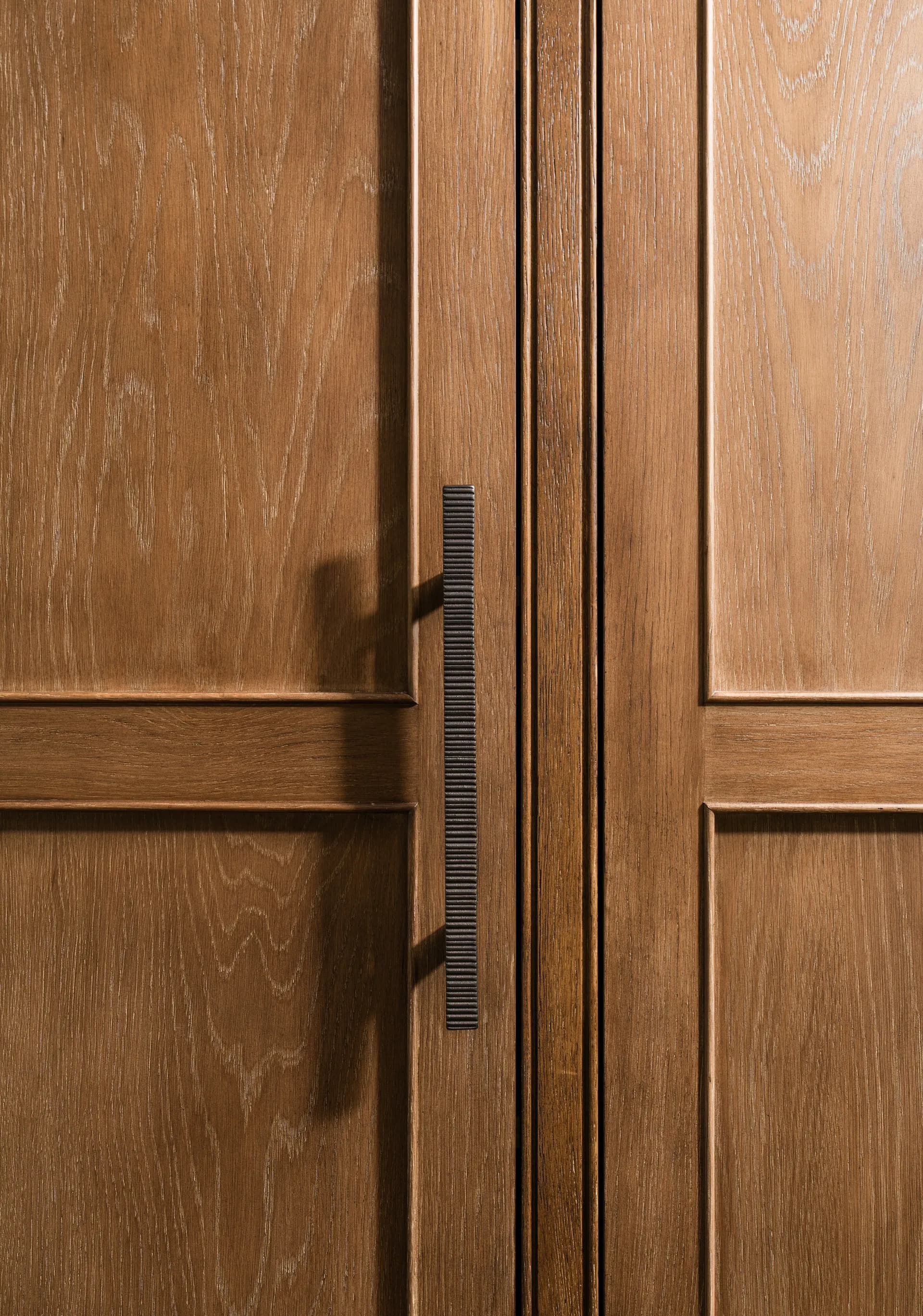 Custom wood cabinet doors with rich grain pattern and sleek bronze linear handles showcasing luxury craftsmanship House Rupert interior design Santa Barbara and Montecito