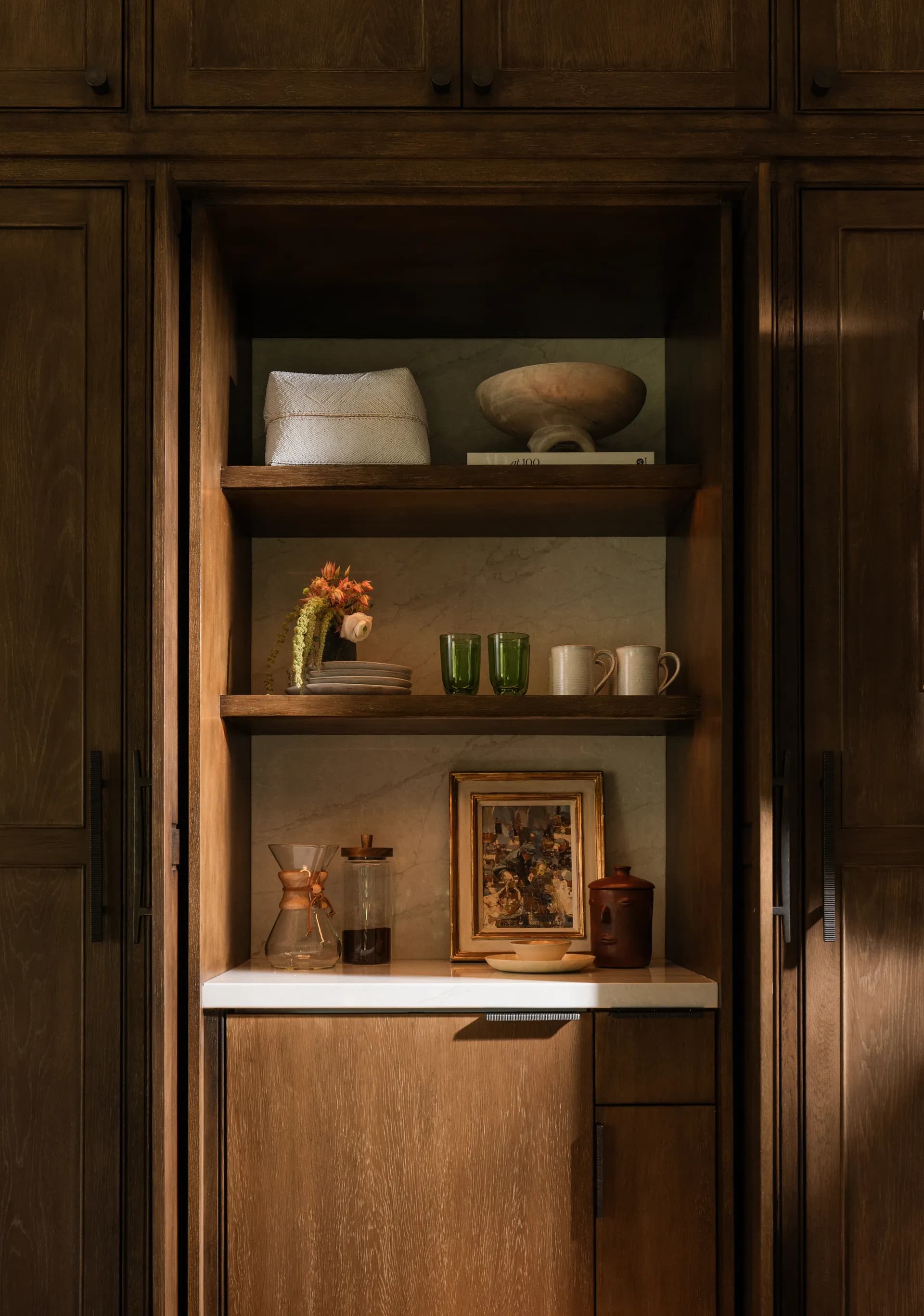 Walnut wood kitchen niche with floating shelves displaying ceramic bowls, green glassware, and coffee accessories, House Rupert interior design Santa Barbara and Montecito