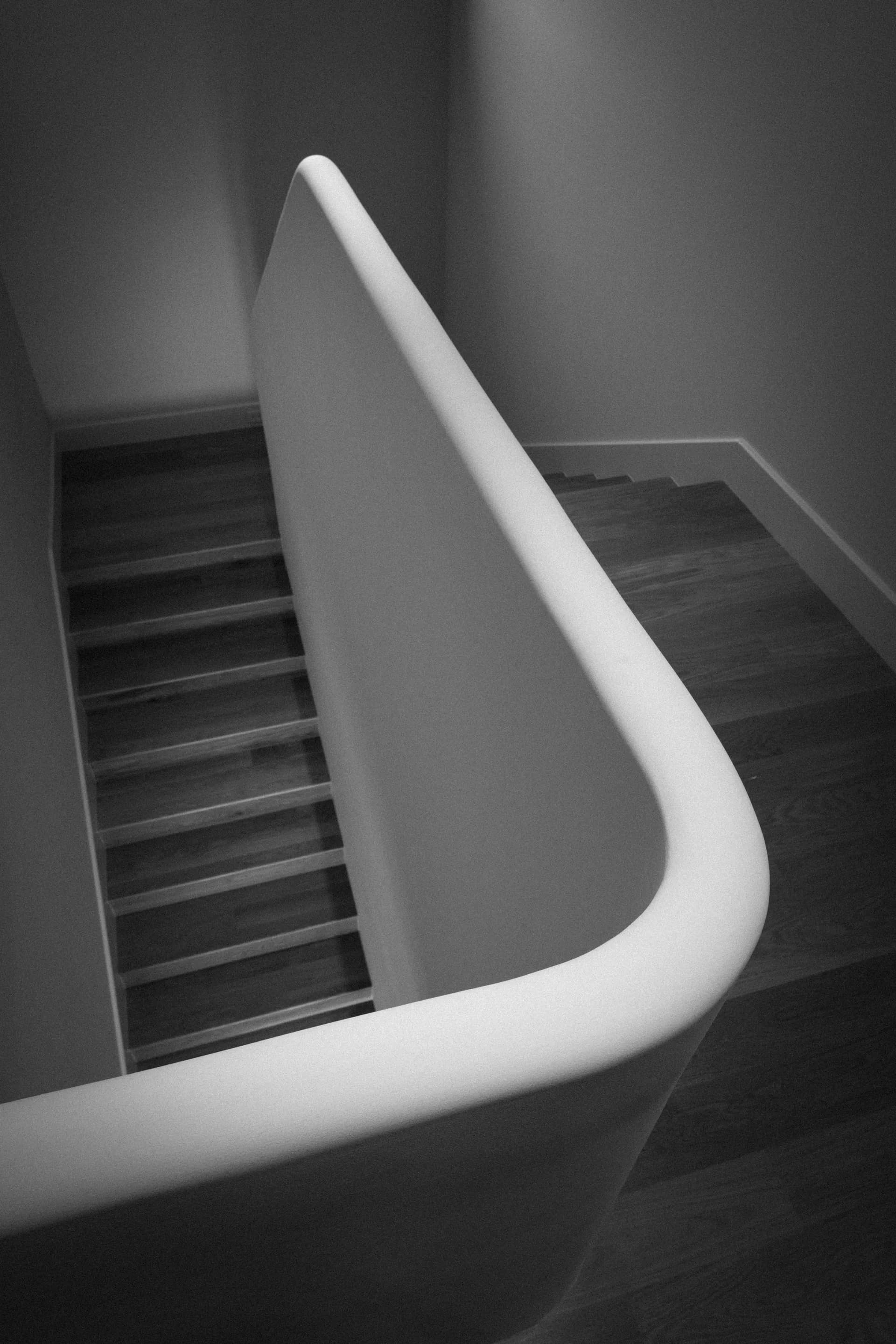 Elegant curved white handrail detail on modern staircase with clean geometric lines and minimalist design House Rupert interior design Santa Barbara and Montecito