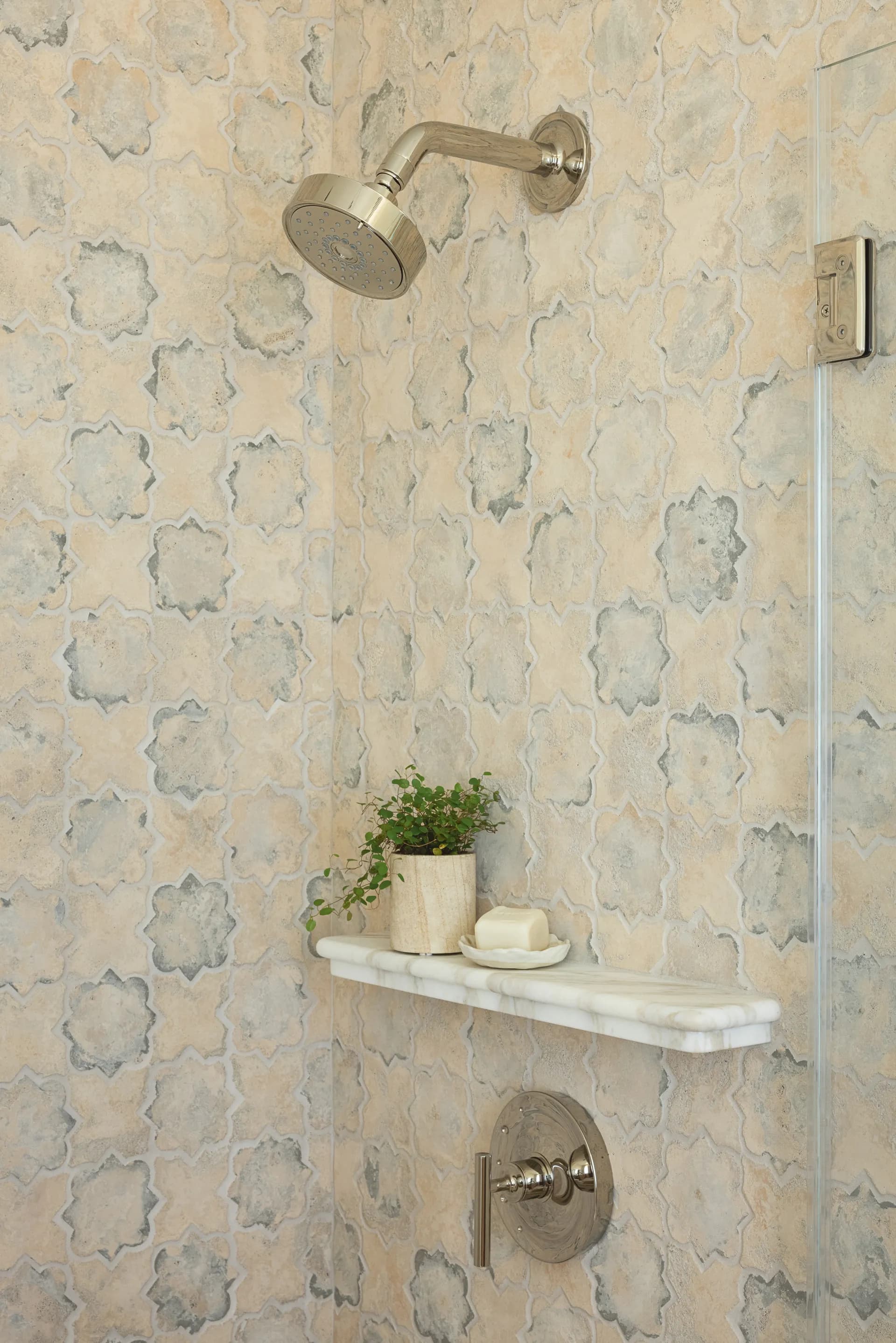 Luxury shower featuring Moroccan star pattern tile walls, brass fixtures, marble corner shelf with plant and soap accessories House Rupert interior design Santa Barbara and Montecito