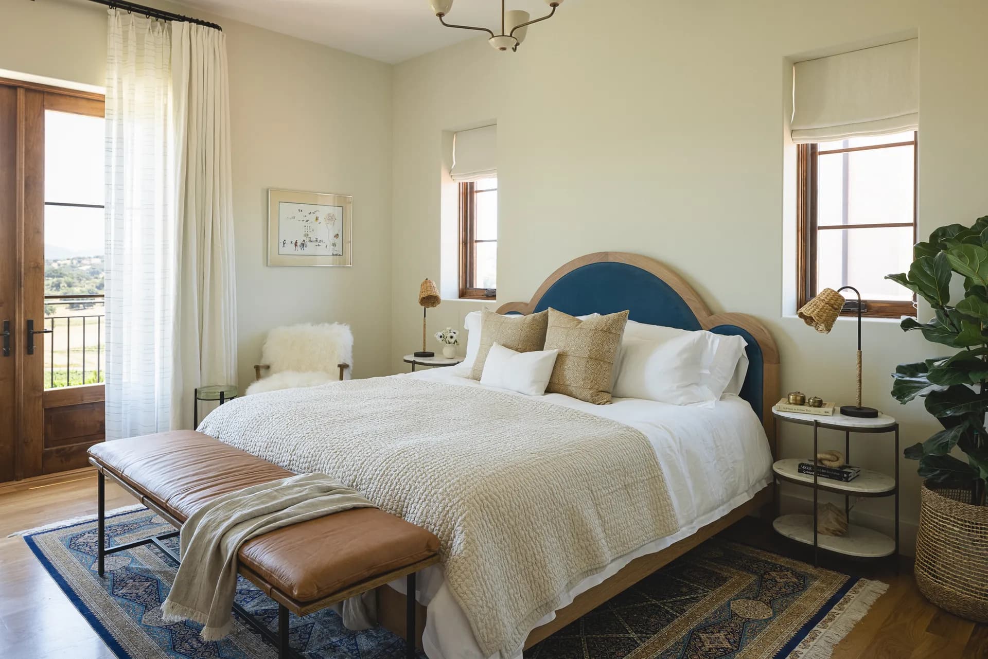 Modern bedroom featuring navy blue and wood headboard, leather bench, neutral bedding, and natural textures House Rupert interior design Santa Barbara and Montecito