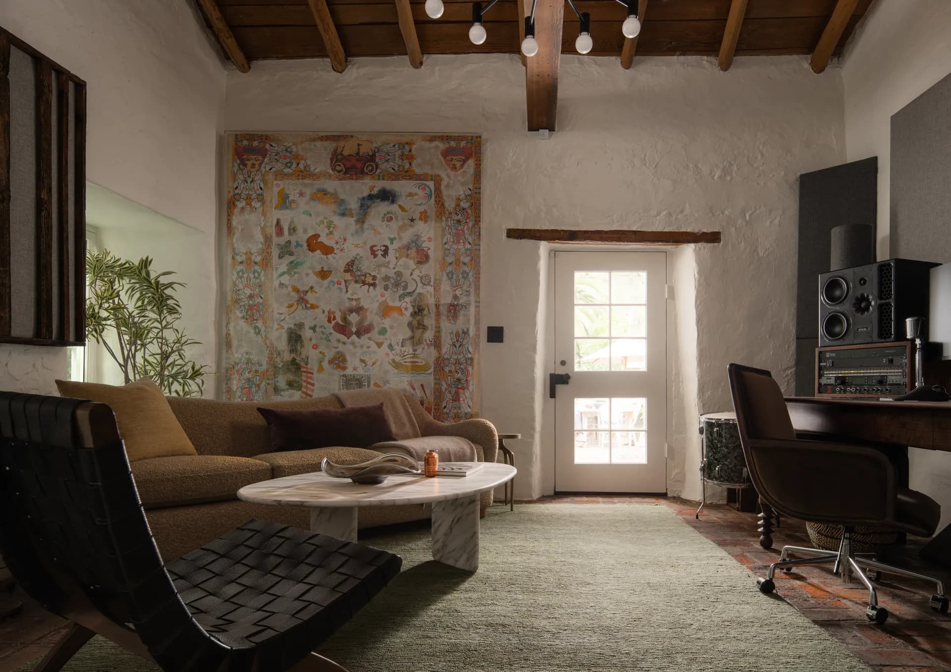 Southwestern living room featuring exposed wood ceiling beams, colorful wall mural, modern sectional sofa, and marble coffee table House Rupert interior design Santa Barbara and Montecito