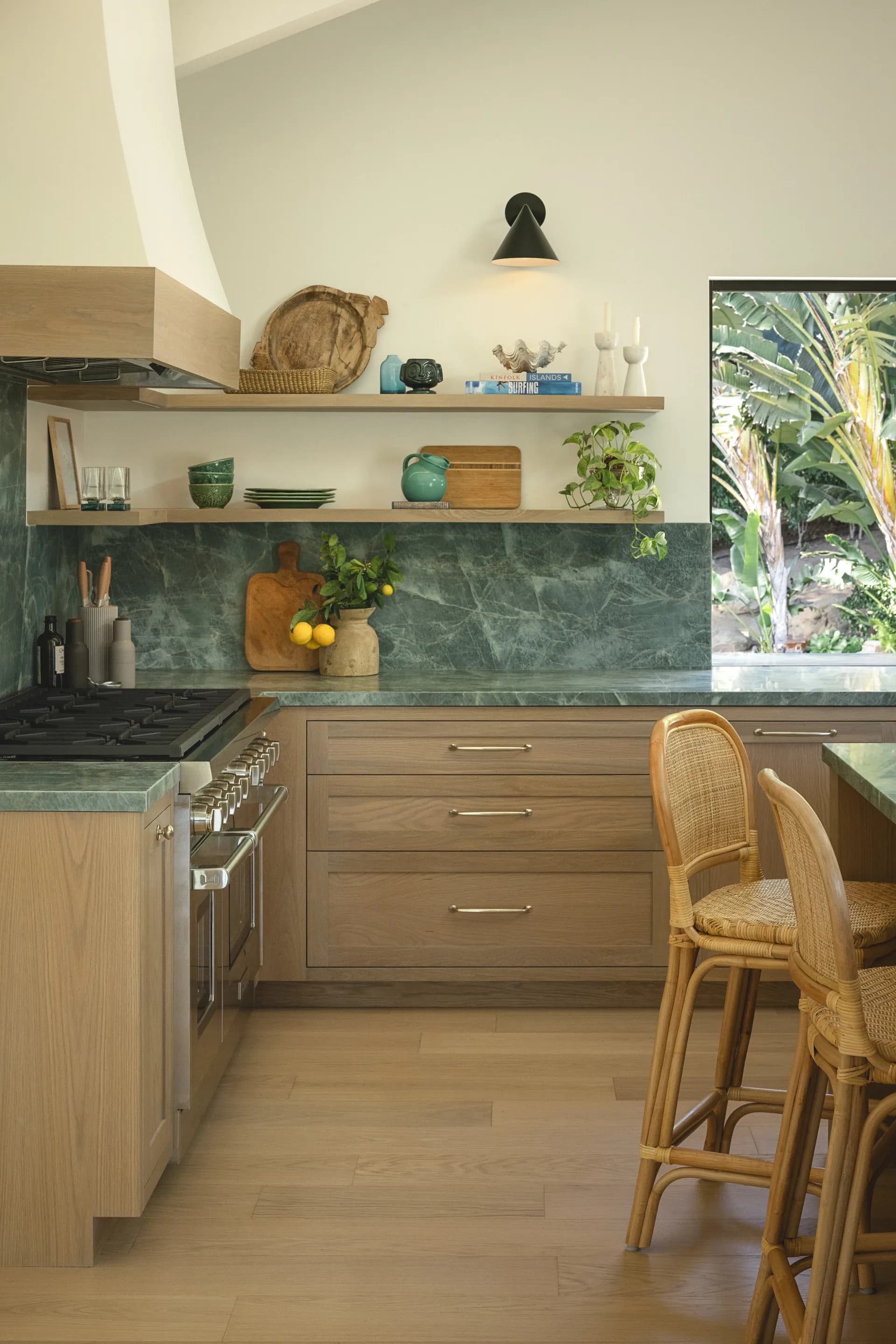 Modern kitchen featuring green marble backsplash and countertops with natural wood cabinetry and rattan bar stools House Rupert interior design Santa Barbara and Montecito
