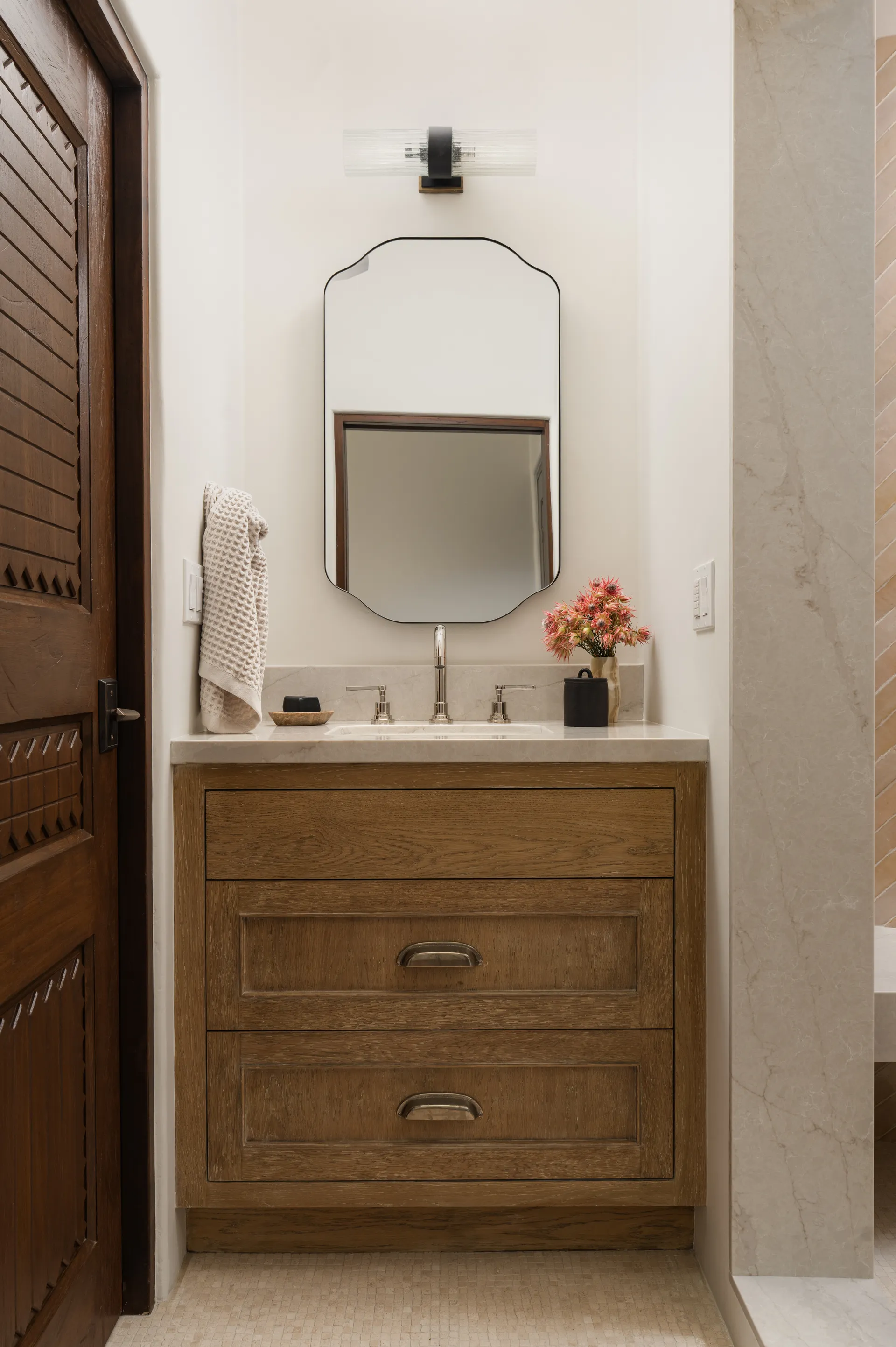 Modern powder room featuring warm wood vanity with white quartz countertop and octagonal black-framed mirror House Rupert interior design Santa Barbara and Montecito