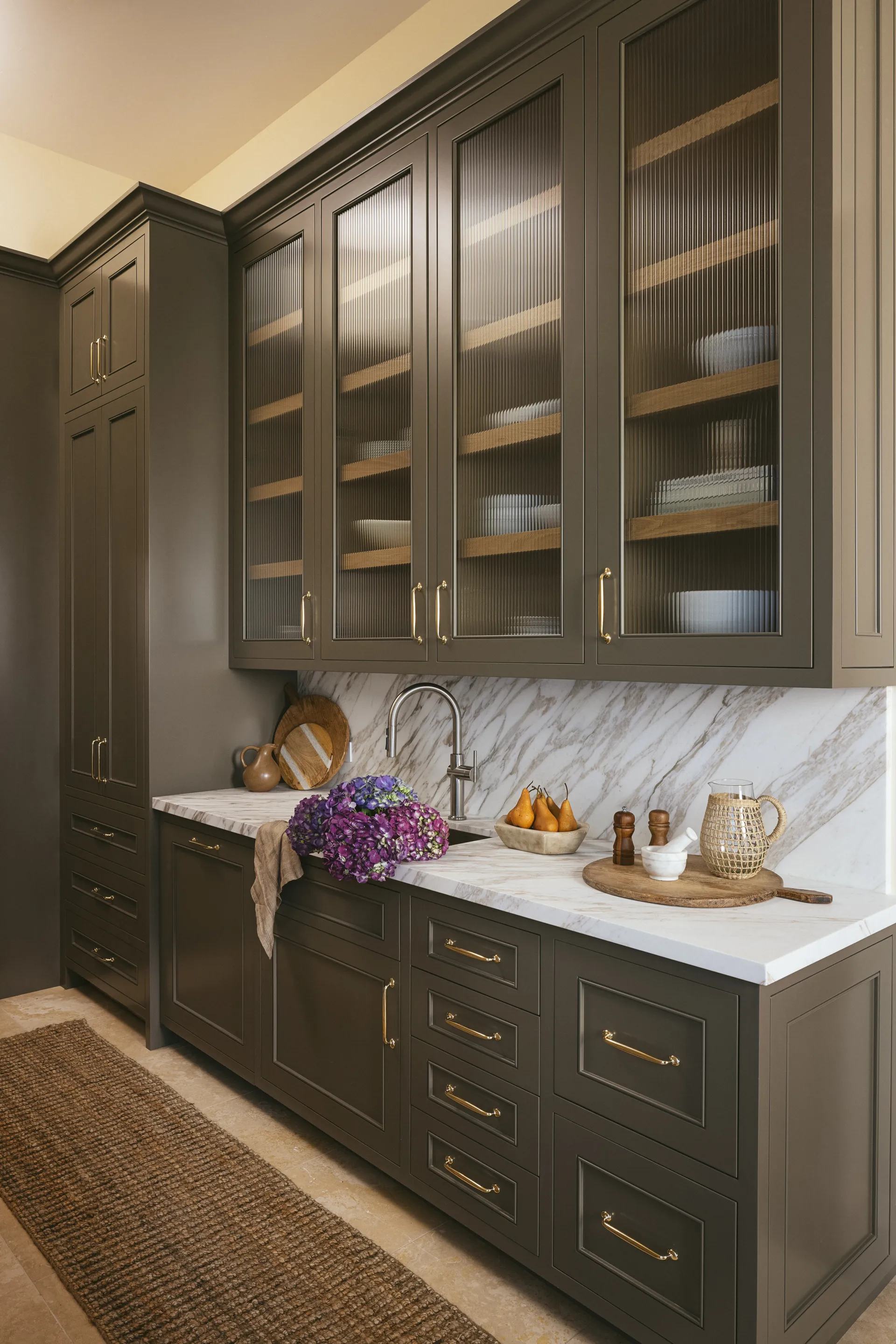Sophisticated butler's pantry featuring dark olive green cabinets with reeded glass doors, white marble countertops, and brass hardware, House Rupert interior design Santa Barbara and Montecito